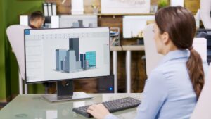 Arquitecta trabajando en un modelo 3D de edificios en ordenador en una oficina de diseño.