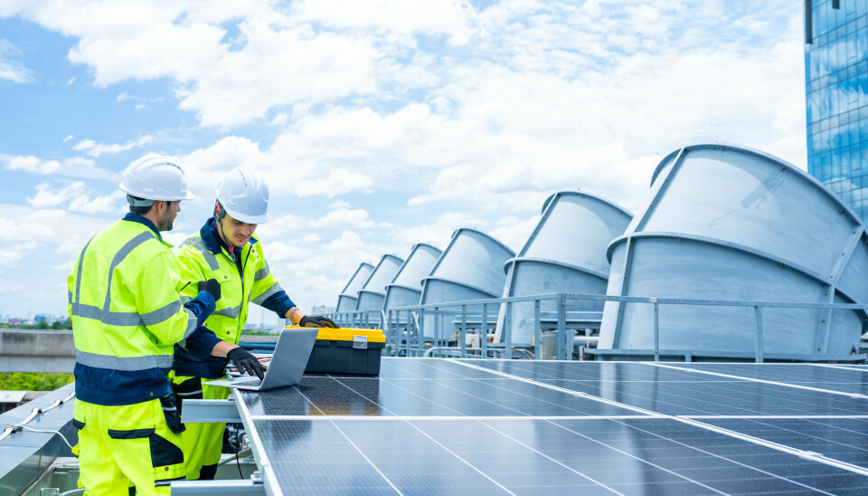 Técnicos con ropa de alta visibilidad instalando o revisando paneles solares en una planta de energía renovable industrial.