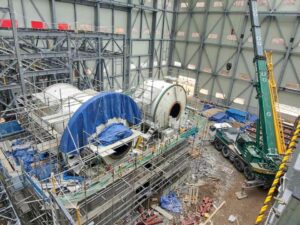 Interior de una instalación industrial de gran tamaño con estructuras metálicas y equipos tecnológicos en proceso de construcción o montaje.