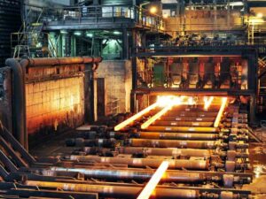 Línea de producción industrial en una acería con acero al rojo vivo siendo procesado en una planta metalúrgica.