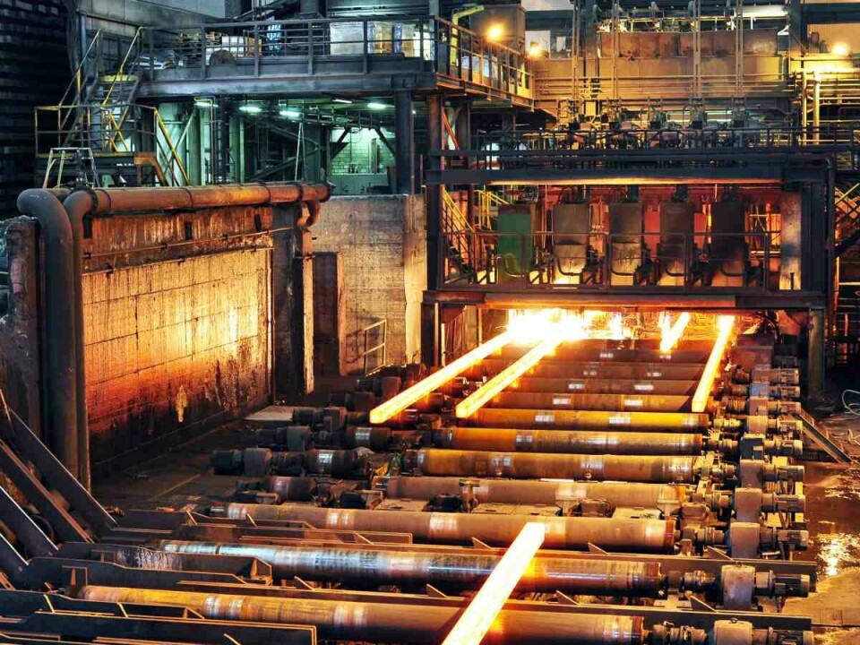 Línea de producción industrial en una acería con acero al rojo vivo siendo procesado en una planta metalúrgica.