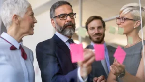 Profesionales trabajando con notas adhesivas para elaborar un plan de negocio paso a paso.