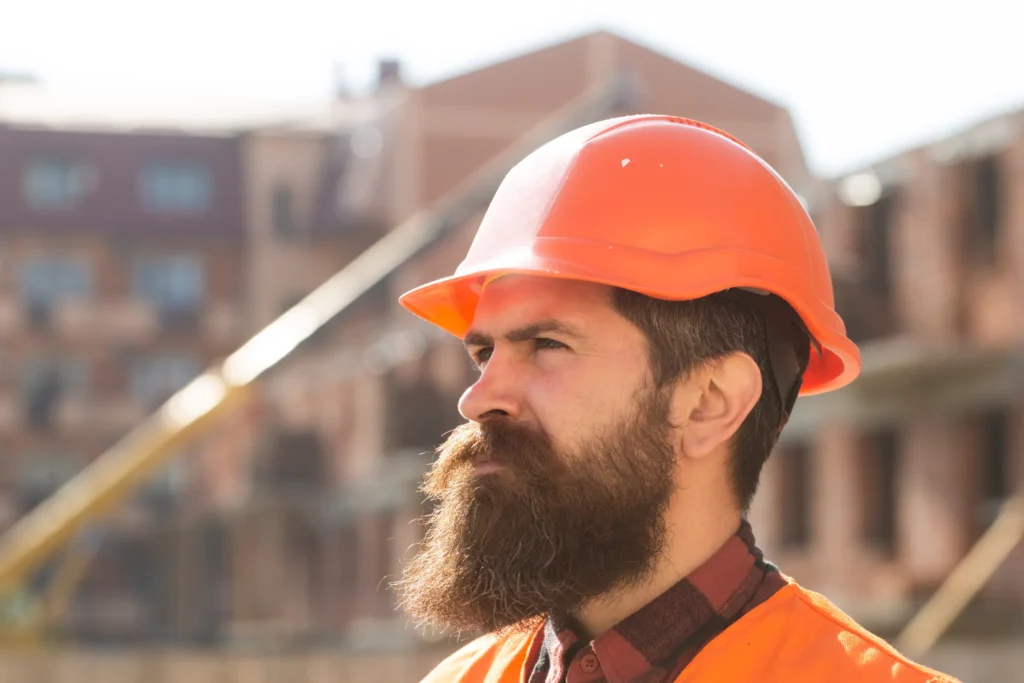 Trabajador de la construcción con casco de seguridad naranja en una obra.