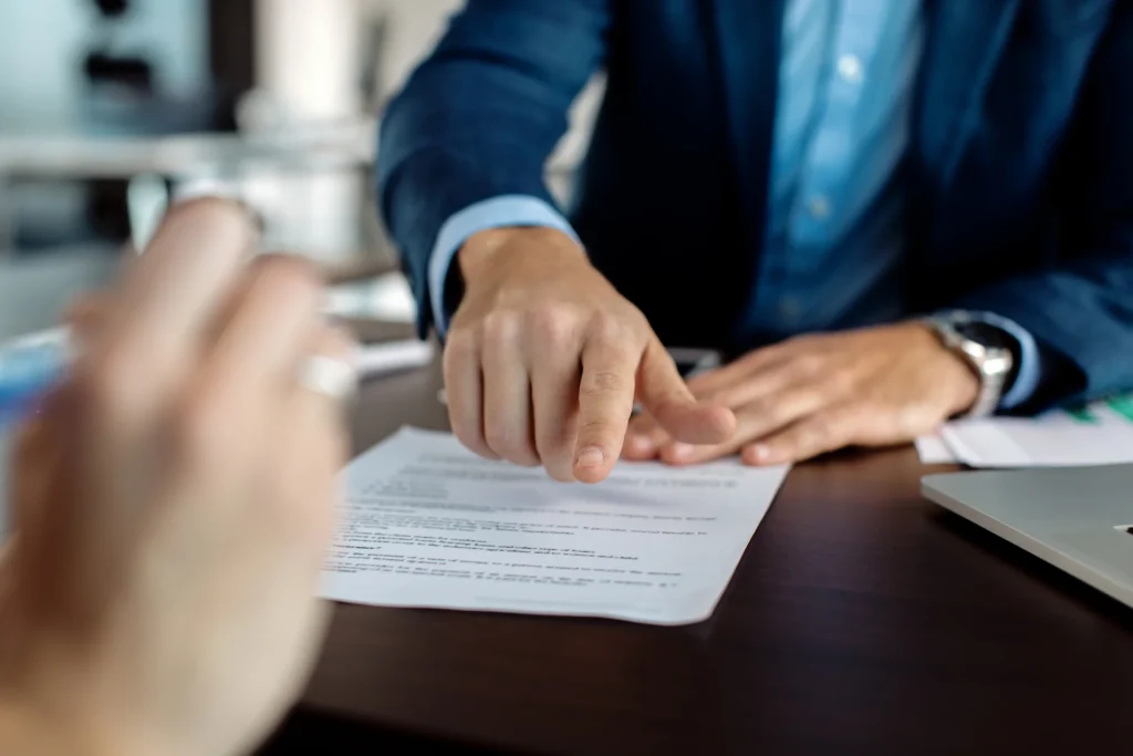 Abogado señalando el lugar de firma en un contrato durante una reunión con un cliente