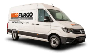 Furgoneta grande Volkswagen Crafter blanca rotulada con el logo de Iberfurgo y el texto "Alquiler de furgonetas", vista de tres cuartos delantera sobre fondo blanco.