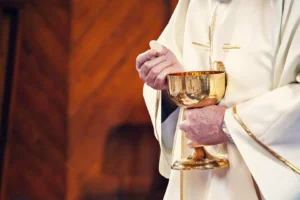 Sacerdote con casulla blanca sosteniendo el cáliz y la hostia durante la celebración de la Eucaristía.